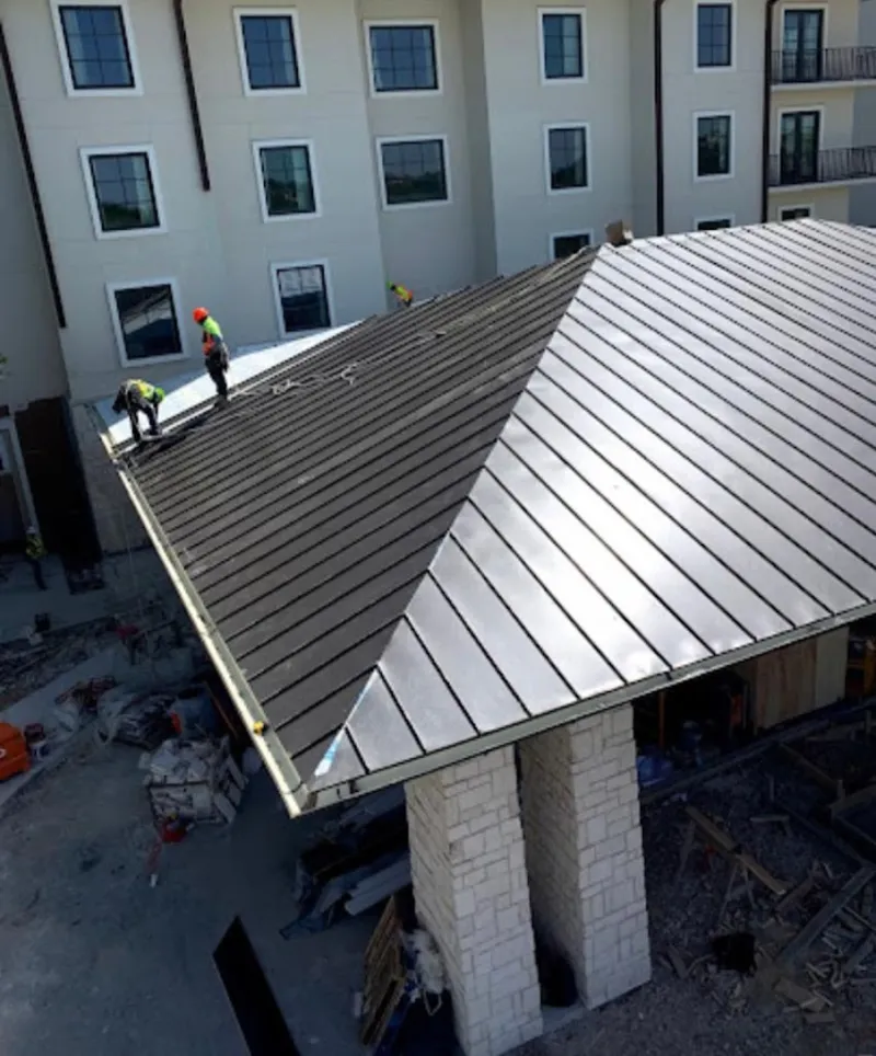 Crew installing standing seam metal roof panels on a commercial project in Bern